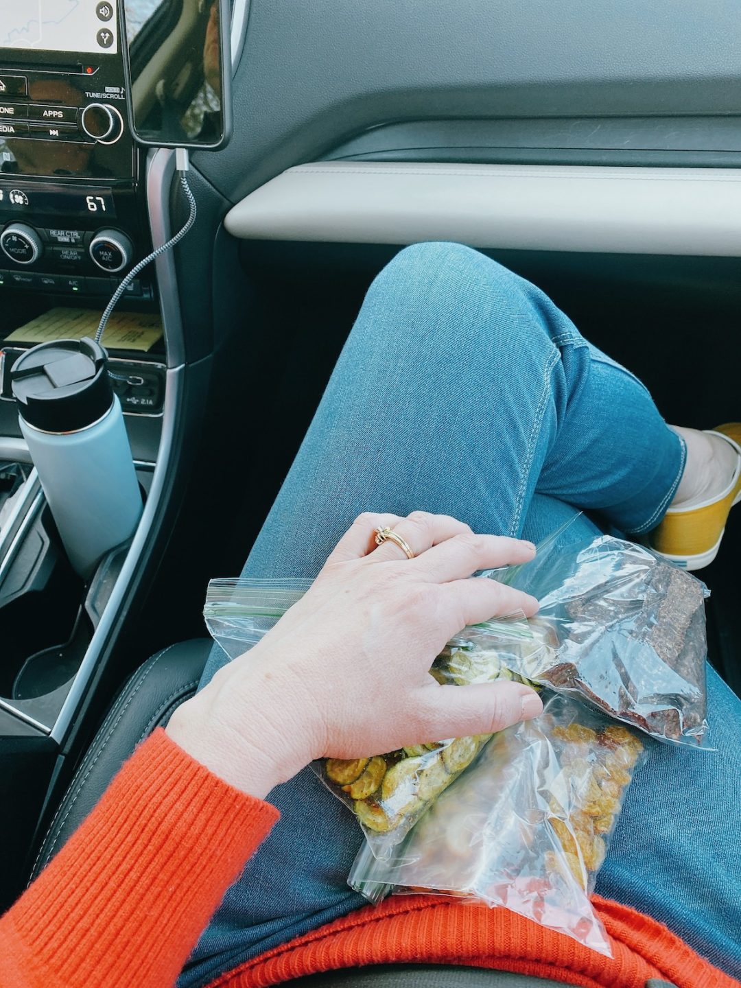 girl in car with bags of snacks on her lap