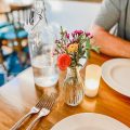 dining table with glass water pitcher and flowers and candle