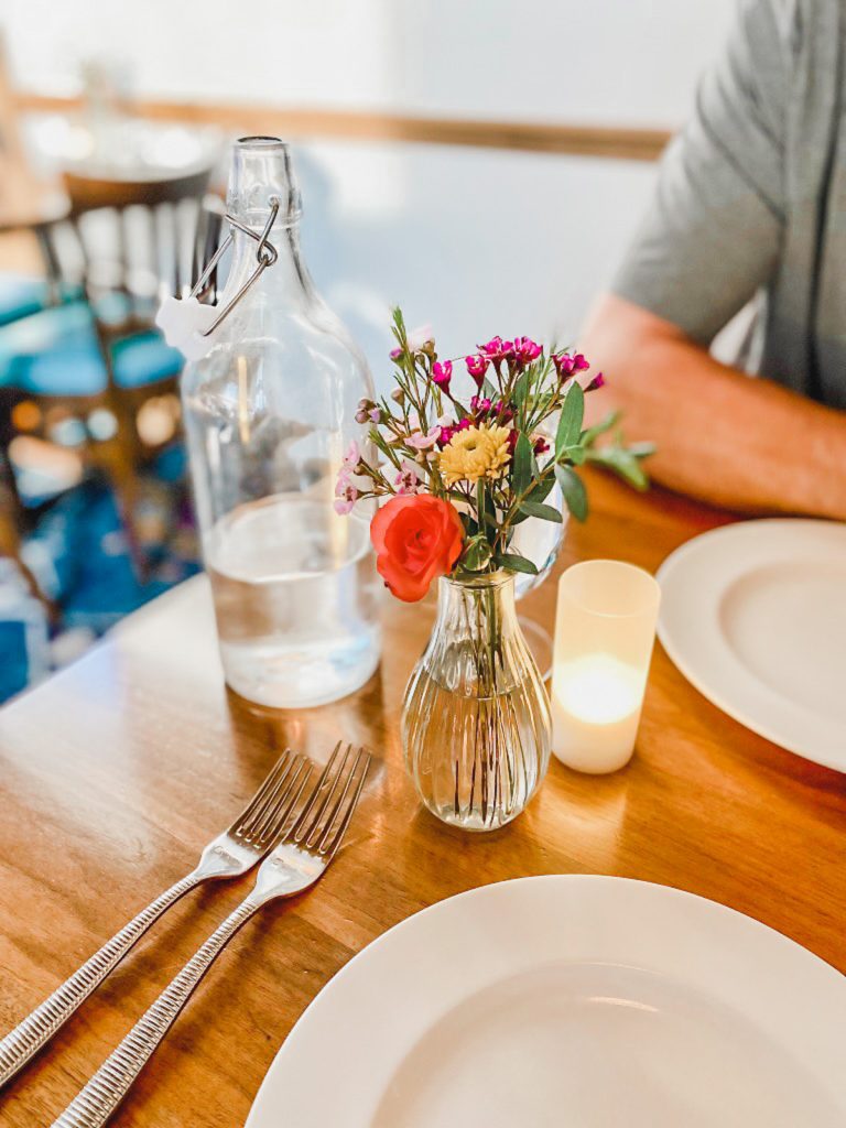 dining table with glass water pitcher and flowers and candle