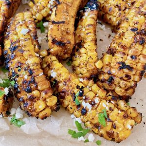 grilled corn on the cob that has been quartered with Mexican spices on it