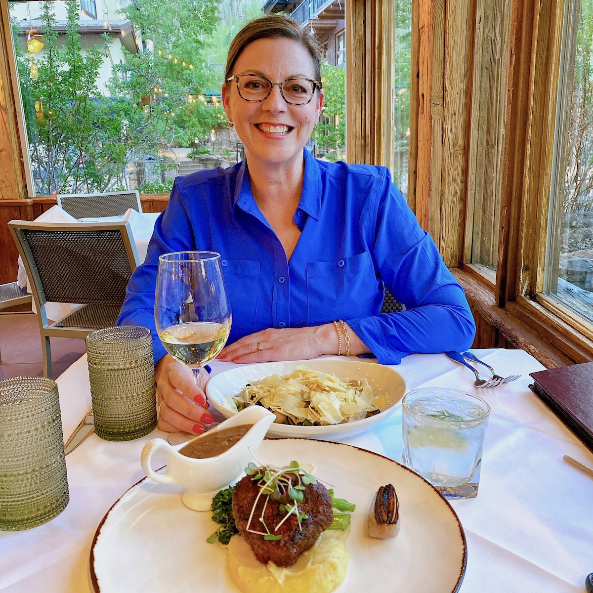 Lyndi Fultz smiling with a raised wine glass at a dinner table