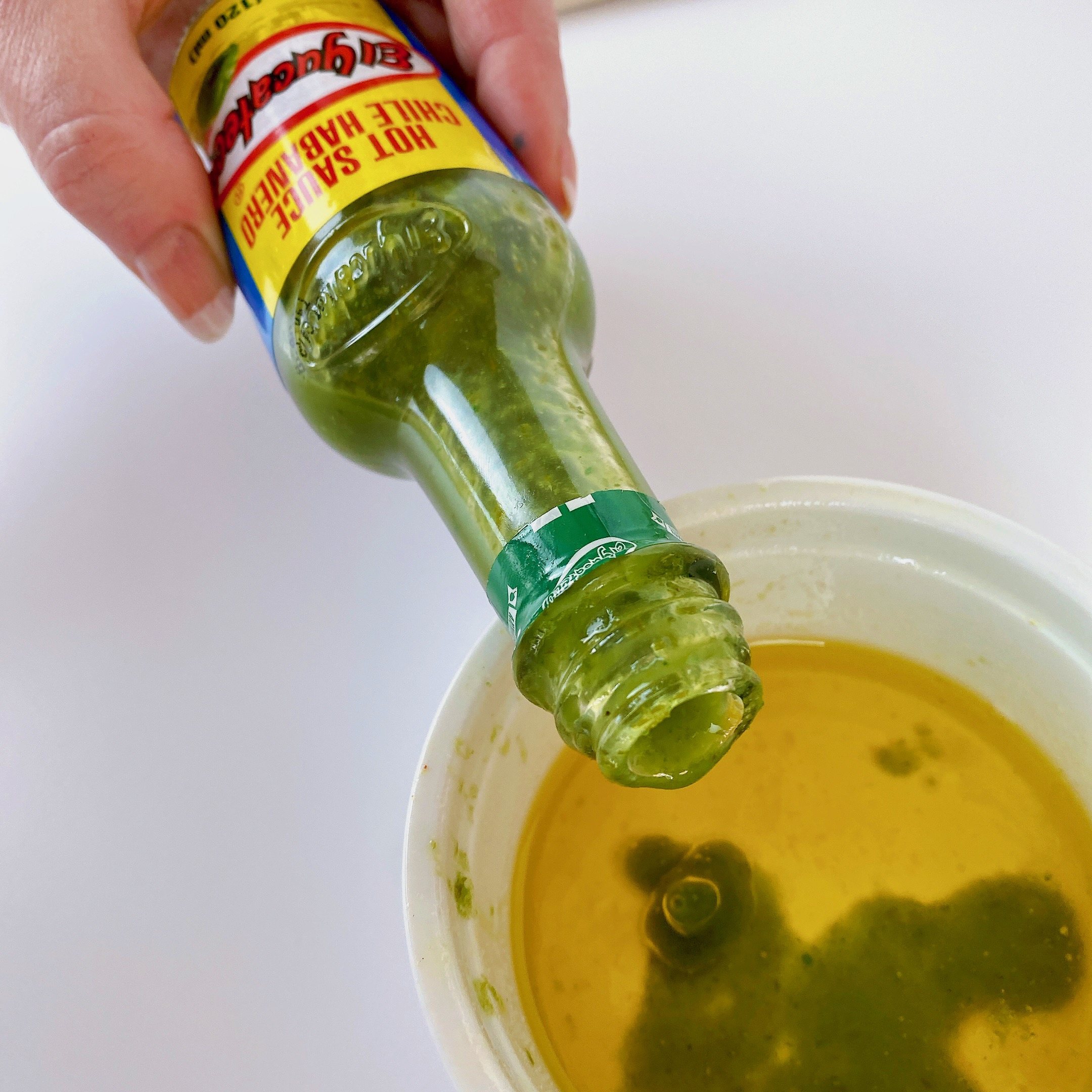 pouring El Yucateco hot sauce in bowl of butter